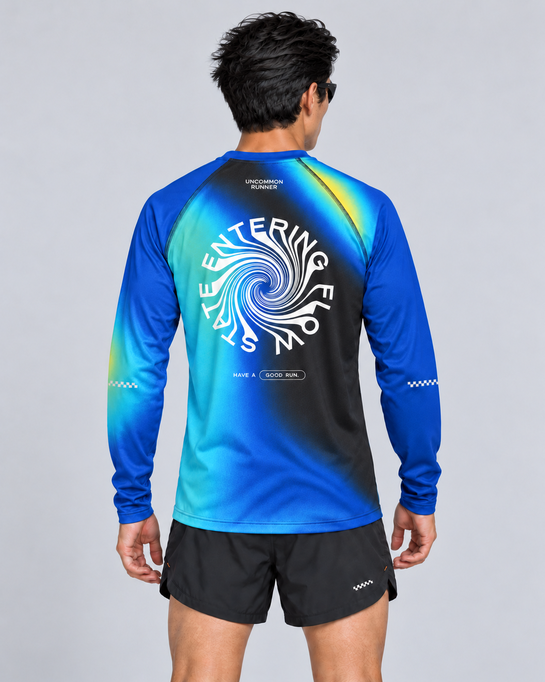 Back studio view of a male model wearing the Entering Flow State long-sleeve TempoTech running tee with black Phanto-3 race shorts