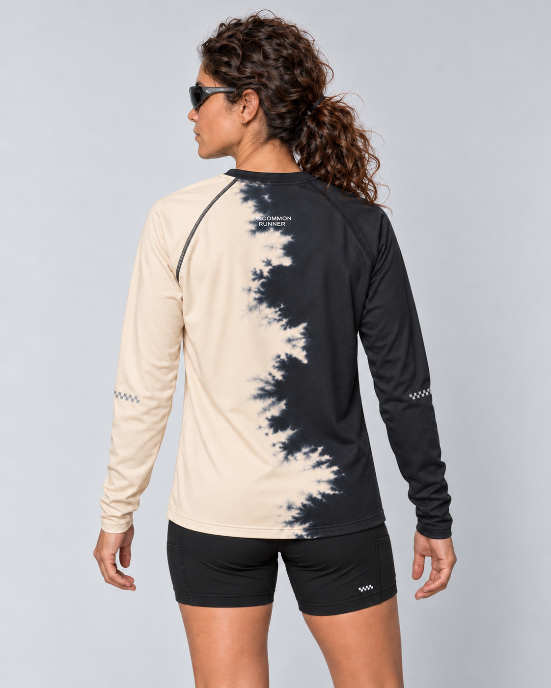Back studio view of a female model wearing the Half Dye long-sleeve TempoTech running tee with upper-back wordmark and sleeve checker details