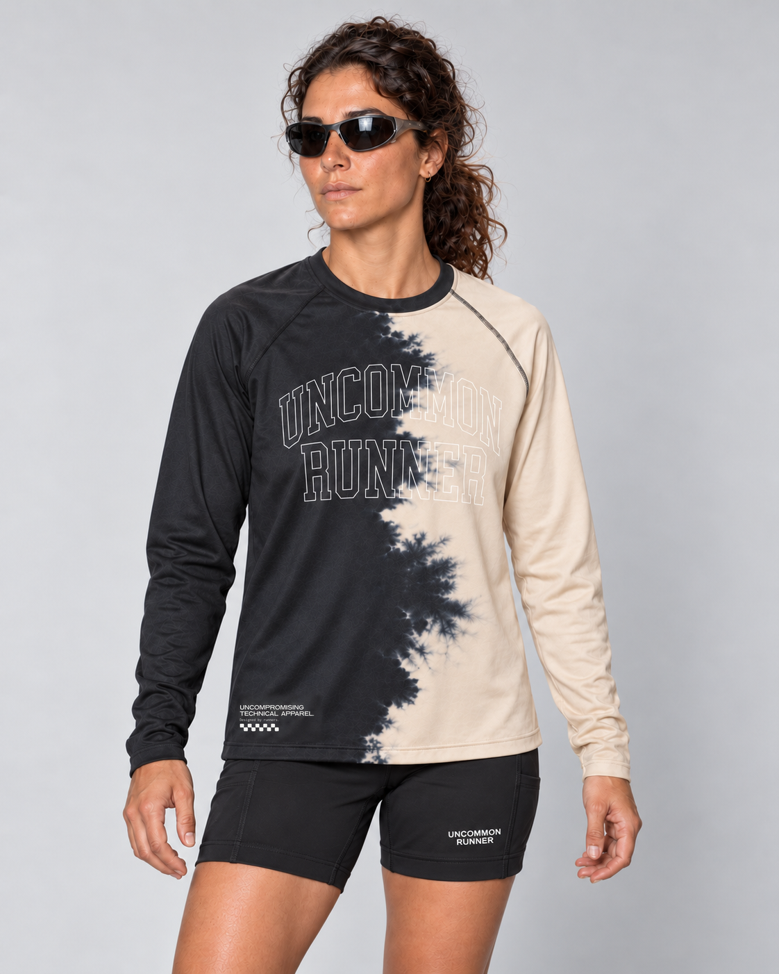 Front studio view of a female model wearing the charcoal and cream Half Dye long-sleeve TempoTech running tee with black Shift-5 shorts