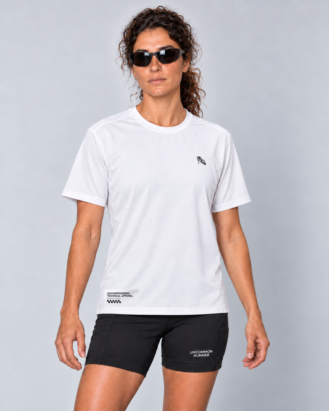 Front studio view of a female model wearing the white Three Ways short-sleeve TempoTech running tee and black Shift-5 shorts