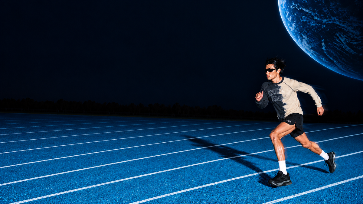 Runner wearing the Half Dye long sleeve top and black Phanto-3 shorts on a blue track beneath a blue planet