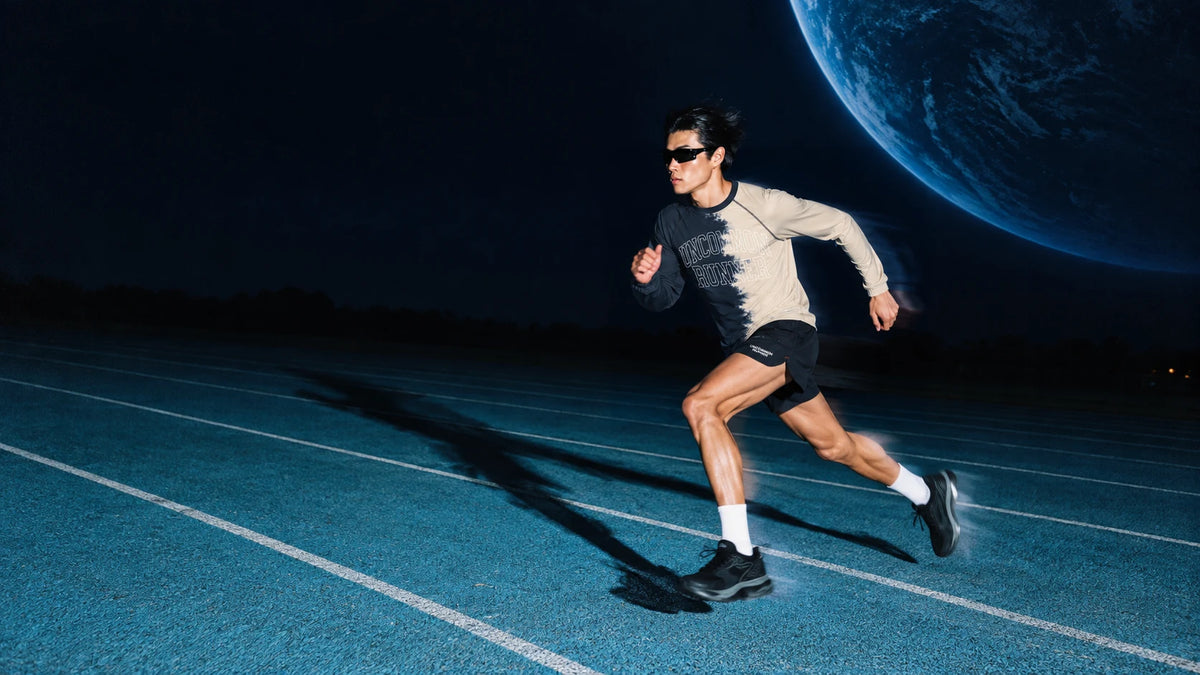 Runner wearing the Half Dye long sleeve top and black Phanto-3 shorts on a blue track beneath a blue planet
